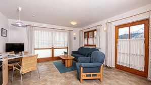 Een woonkamer met een bank, stoelen, een eettafel en een televisie.