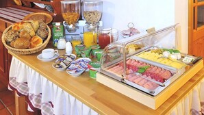 Een ontbijtbuffet met diverse etenswaren, zoals brood, ontbijtgranen, fruit en drankjes.