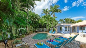 A backyard with a swimming pool, lounge chairs, and a small building.