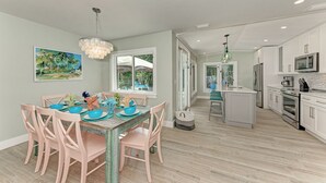 A modern kitchen with white cabinets, stainless steel appliances, and a dining area with a wooden table and chairs.