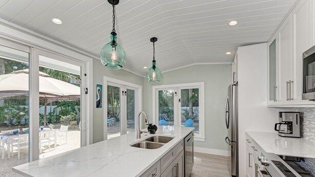 A modern kitchen with a large island, stainless steel appliances, and a view to the outdoor patio.