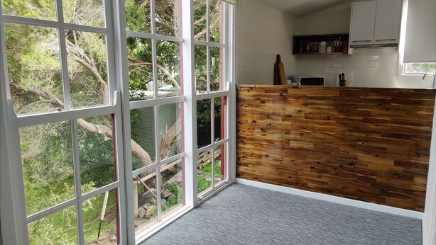 Una cocina con un amplio ventanal corredera, una pared de acento de madera y vistas al exterior con vegetación.