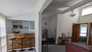 Una cocina moderna con armarios blancos, encimera de madera y una zona de estar con sofá rojo y una pequeña mesa.