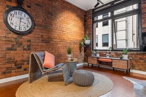 Relax in a warm, inviting space with a comfortable chair, a potted plant, and a large window.