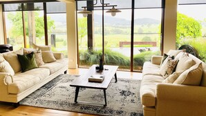 A spacious living room with large windows, a wooden coffee table, and two sofas.