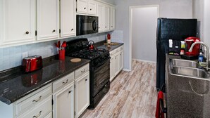 A kitchen with white cabinets, a black stove, stainless steel sink, and a red toaster. - Remodeled Broken Arrow Home -Dogs OK -Safe Location -Fully Privacy Fenced Yard  (Broken Arrow)