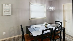 A dining area with a table set for four, a chandelier, and a wall-mounted sign with motivational quotes. - Remodeled Broken Arrow Home -Dogs OK -Safe Location -Fully Privacy Fenced Yard  (Broken Arrow)