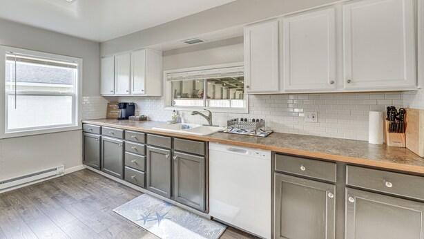 A modern kitchen with white cabinets, a dishwasher, and a countertop with a coffee maker and utensils.