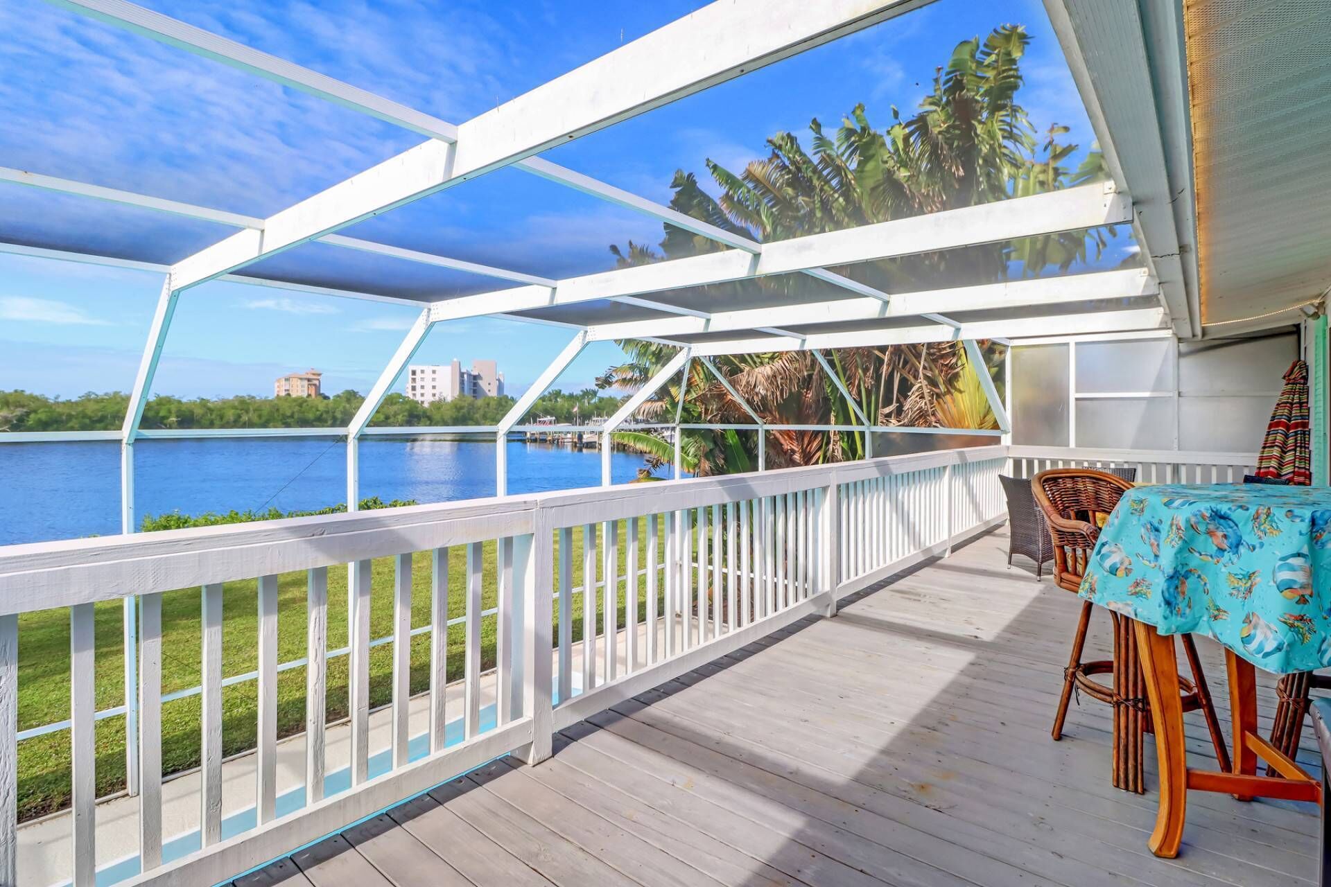 A covered outdoor deck with a view of a lake and buildings in the distance.