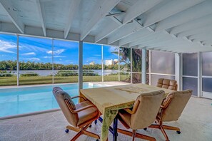 Une salle de réunion moderne, dotée d’une grande table, de chaises confortables et de larges fenêtres offrant une vue sur un lac et des bâtiments.