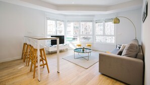 A modern living room with a wooden dining table, a sofa, and a TV. - E 2 BEDROOM FAMILY APARTMENT SAN MARCIAL 33 (San Sebastián)