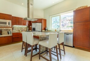 Uma cozinha moderna com armários de madeira, bancada de granito e uma ilha planejada com banquetas.
