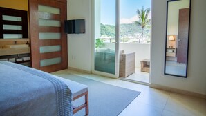 A hotel room with a bed, a TV, a sliding glass door to a balcony, and a large mirror. - New renovated Penthouse in V399! 2BD Penthouse for rent in Old Town, Puerto vall (Puerto Vallarta)