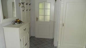 A hallway with a white door, a white cabinet with a mirror, and a tiled floor. - Haferweg 2, Strandnelke EG - Haferweg 2, Strandnelke (Wyk auf Föhr)