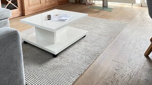 A modern living room with a white coffee table, grey sofa, and a TV on a stand. - Beach time, Germany (List)