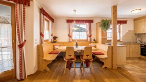 Un tavolo da pranzo in legno con panche, un angolo cottura e una finestra con tende.