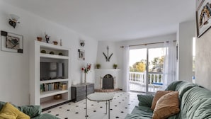 Uma sala de estar com sofá, televisão, lareira e varanda.