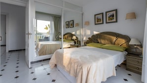 Um quarto com uma cama grande, um espelho, uma mesa de cabeceira e um aparador.