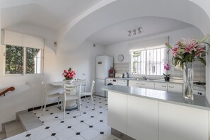A modern kitchen with white cabinets, a central island, and a dining area with chairs.