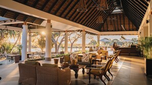 An outdoor seating area with wicker furniture, a bar, and a view of the water. - Chobe Safari Lodge (Kasane)