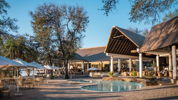 A resort with outdoor seating, a pool, and a covered area with tables and chairs. - Chobe Safari Lodge (Kasane)
