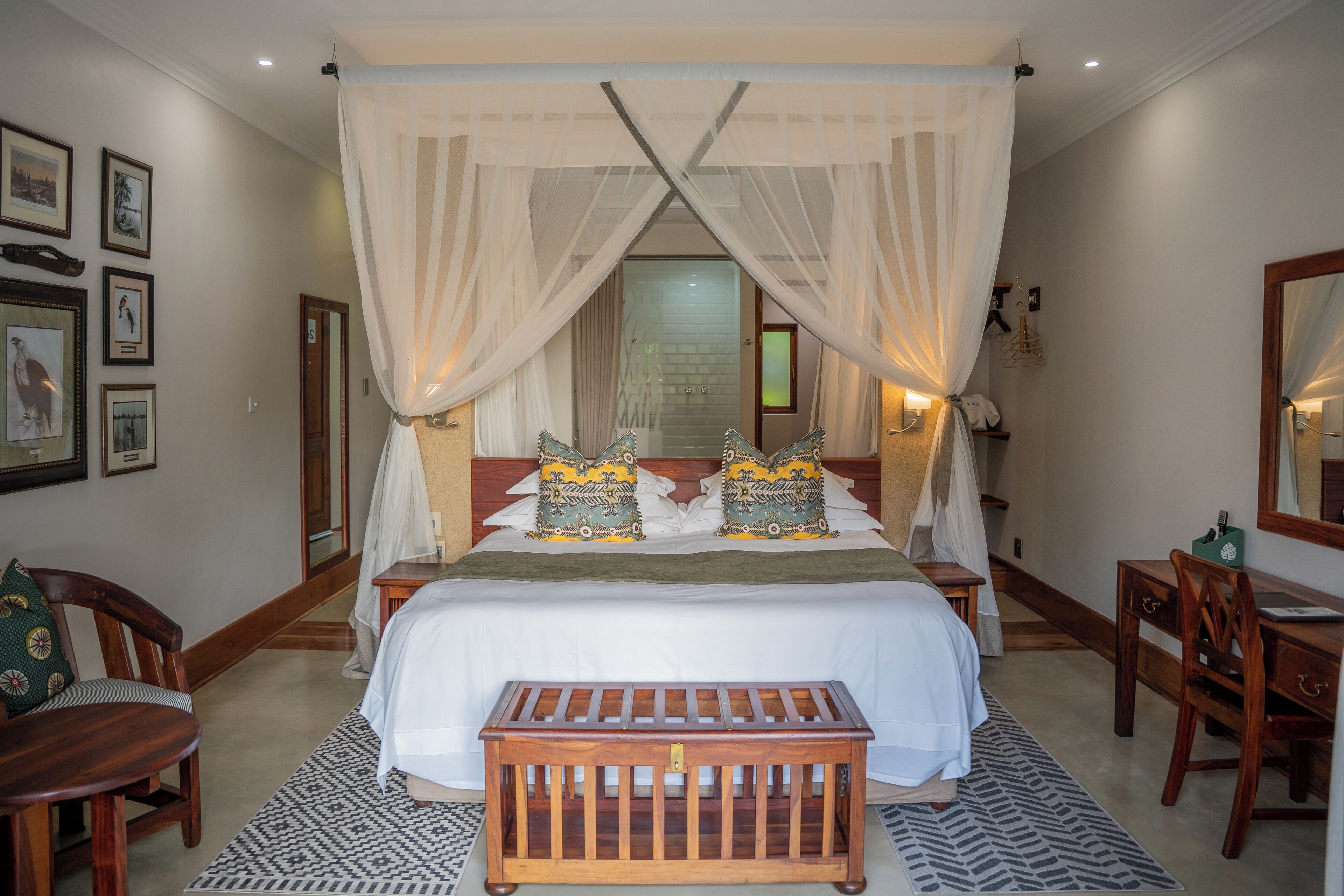 A bedroom with a large bed, a wooden bench, and a desk.