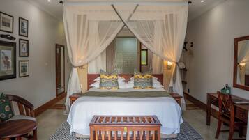A bedroom with a large bed, a wooden bench, and a desk.