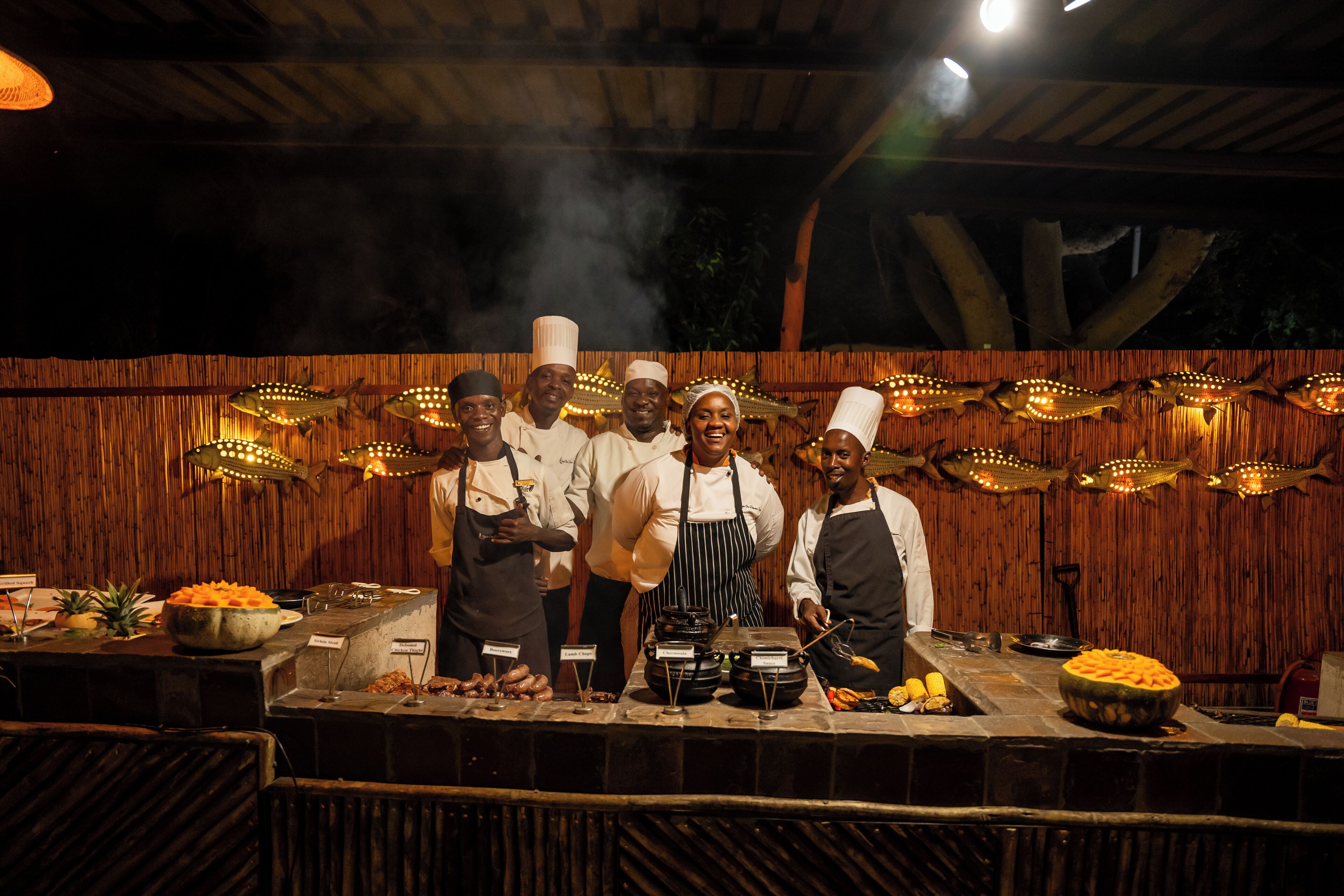 A group of chefs standing in front of a buffet with various dishes and cooking equipment.