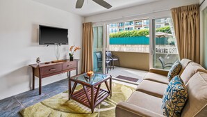 A living room with a sofa, a coffee table, a TV, and a ceiling fan.