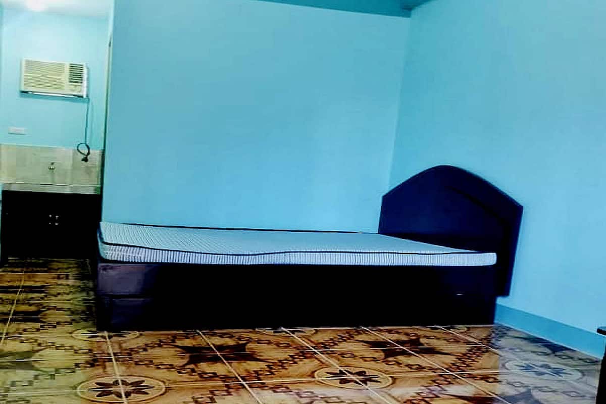 A small room with a bed, a radiator, and patterned flooring.