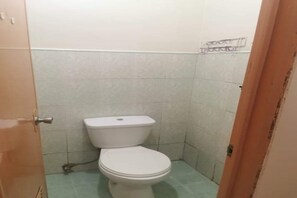 A small, compact bathroom with a toilet, a sink, and a mirror. - OYO 833 Ln Apartelle (Butuan)