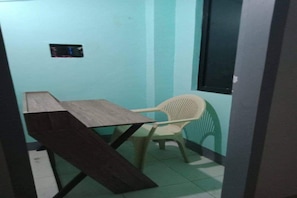 A small room with a wooden table and a plastic chair, a window, and a wall-mounted electrical outlet. - OYO 833 Ln Apartelle (Butuan)