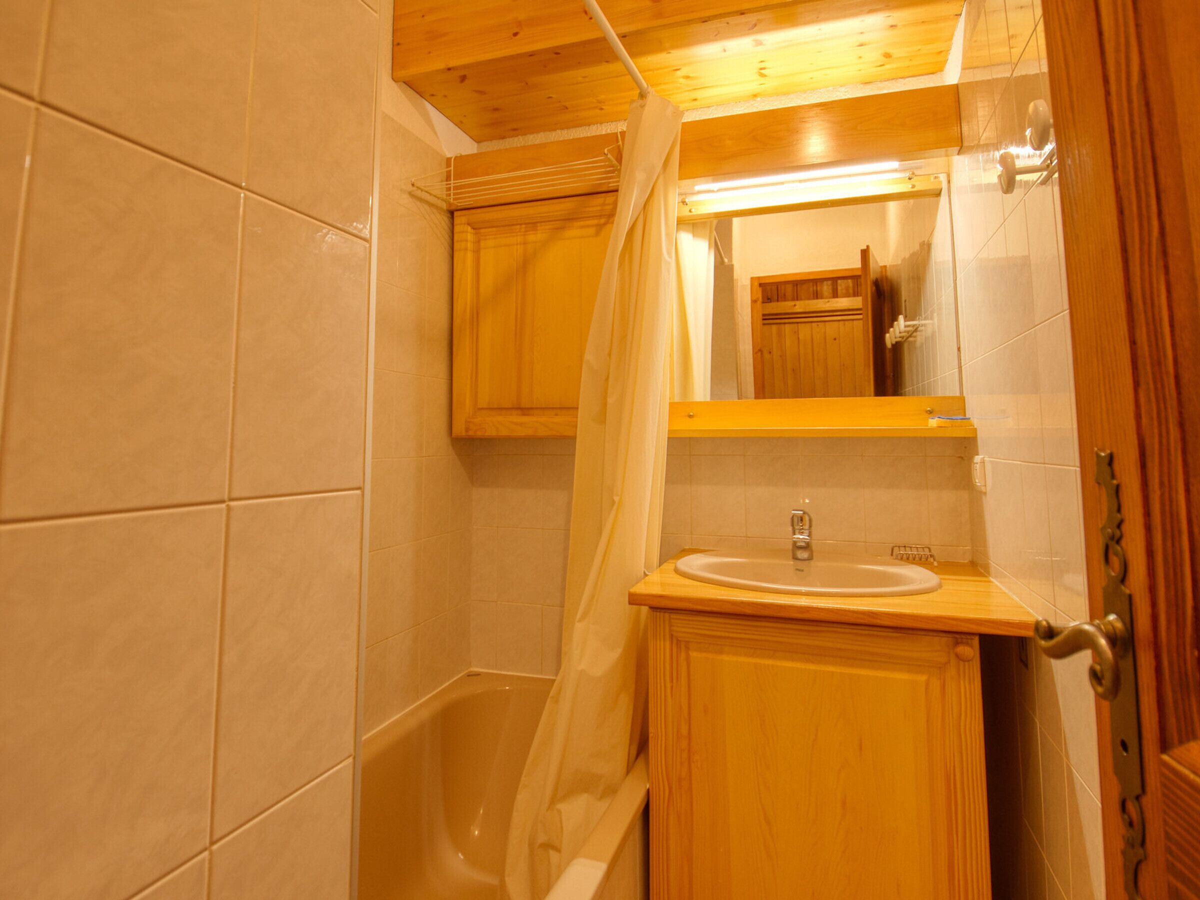 A wooden bathroom with a bathtub, a sink, and a mirror.