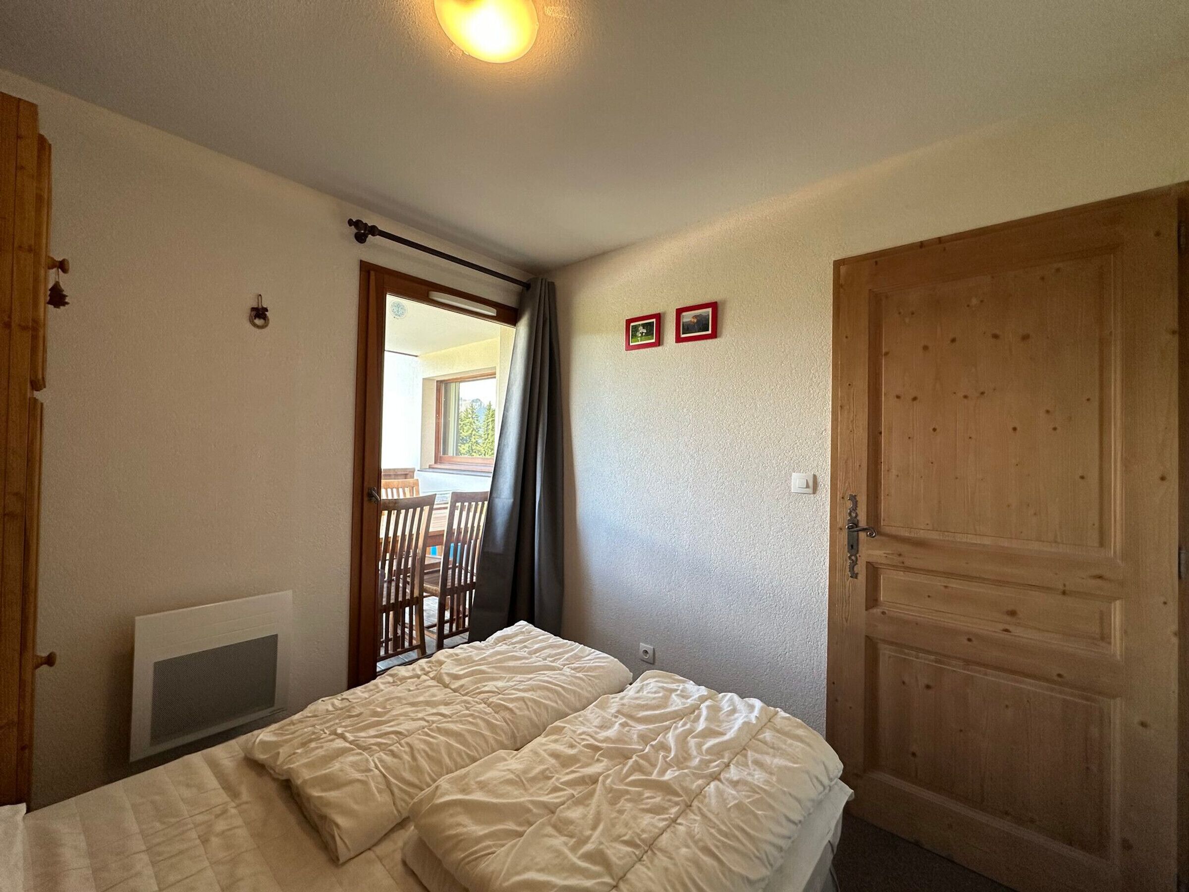 Una camera da letto con un letto, un termosifone, una porta in legno e una finestra con tende.