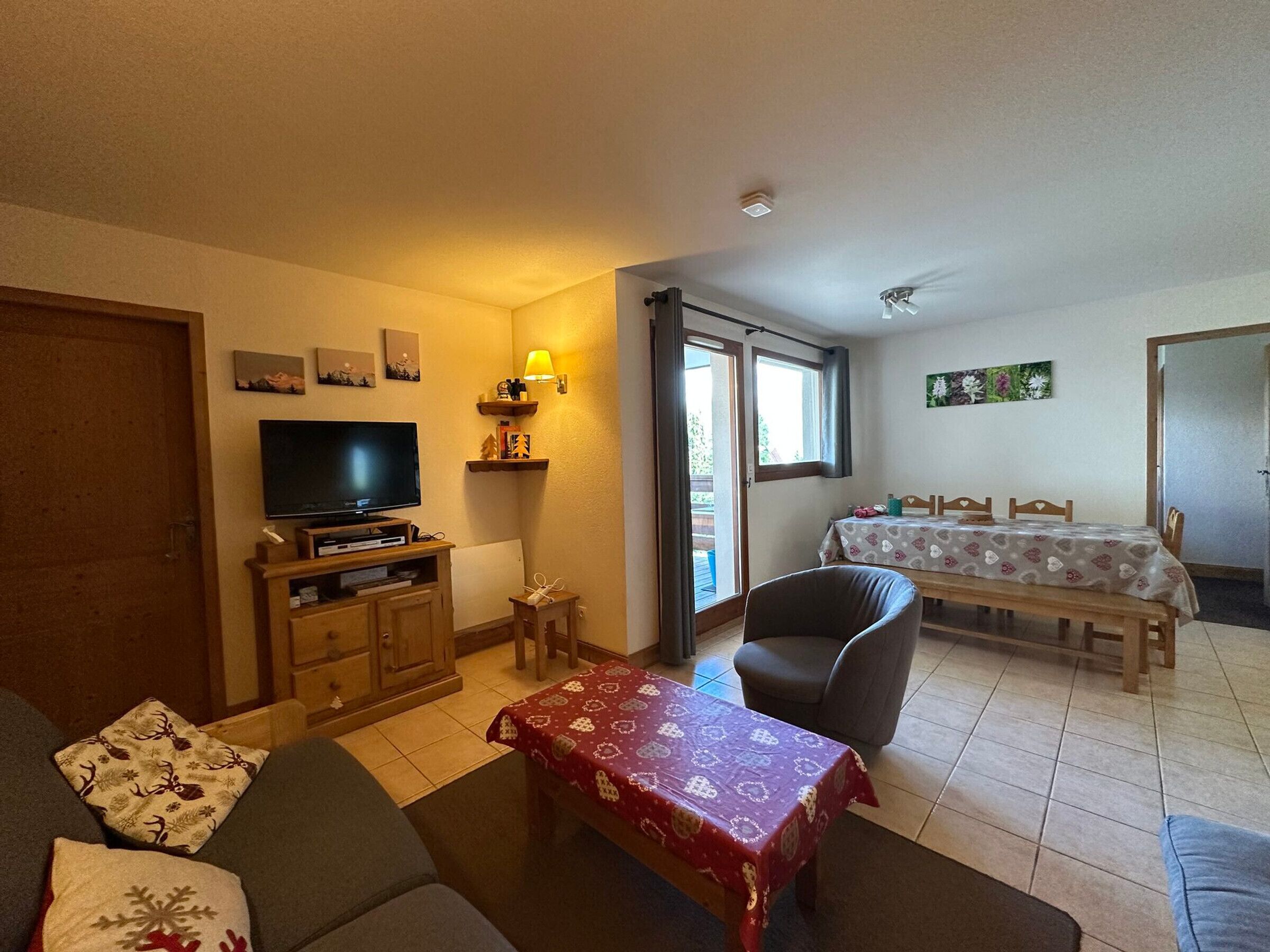 A cozy living room with a television, sofa, and a dining area with a table and chairs.