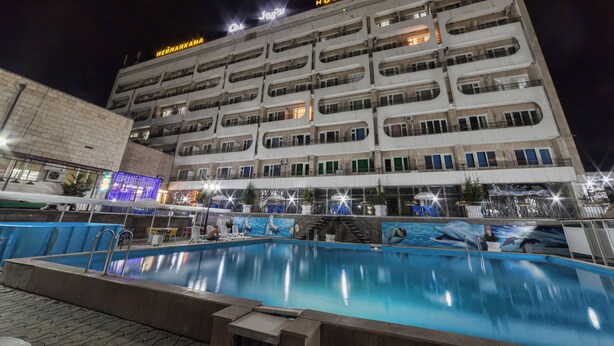 A hotel with multiple balconies and a swimming pool in the foreground. - Osh Nuru (Osh)