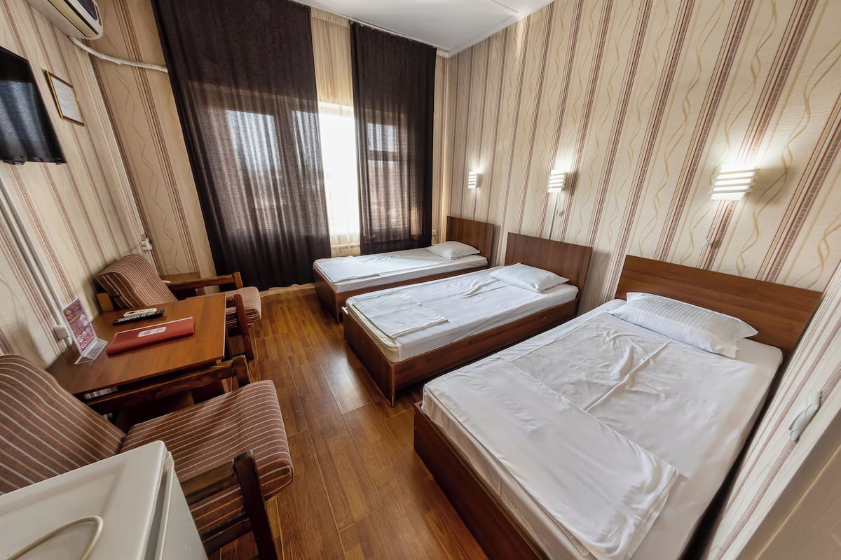A hotel room with two single beds, a wooden desk, a chair, and a small table.