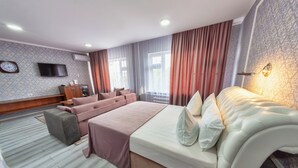 A hotel room with a large bed, a sofa, a TV, and a desk. - Osh Nuru (Osh)