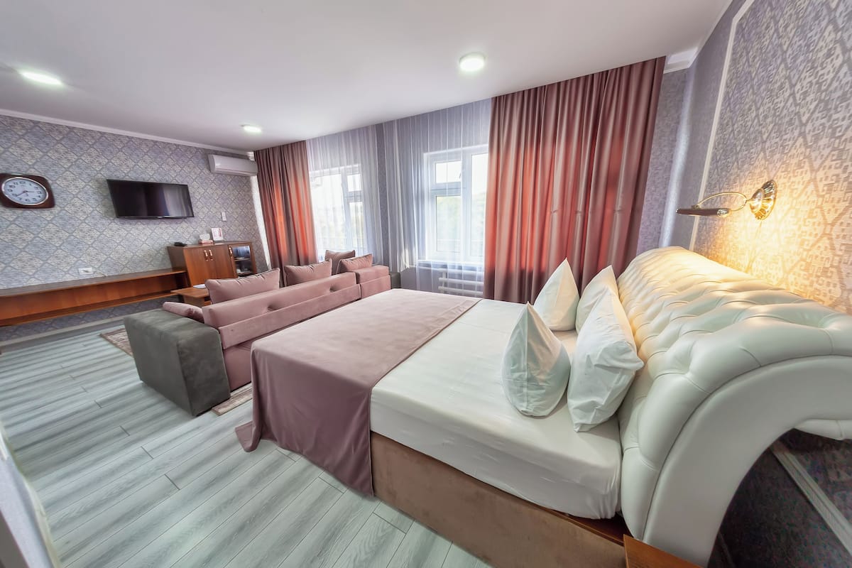 A hotel room with a large bed, a sofa, a TV, and a desk.