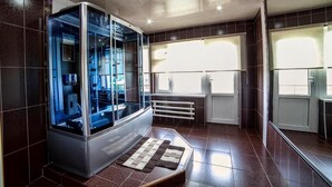 A modern bathroom with a glass-enclosed shower, a built-in toilet, and a large window providing natural light. - Osh Nuru (Osh)