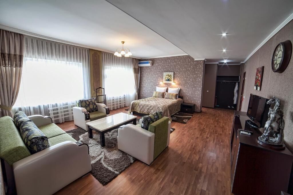 A modern living room with a sofa set, a coffee table, a bed with a headboard, a TV, and a statue.