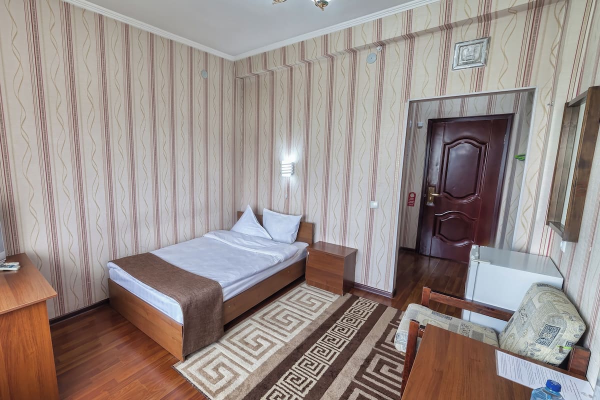 A neatly arranged bedroom with a bed, bedside tables, a TV, and a desk.