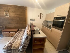 A compact living space with a sofa, a small dining table, and a kitchenette area.