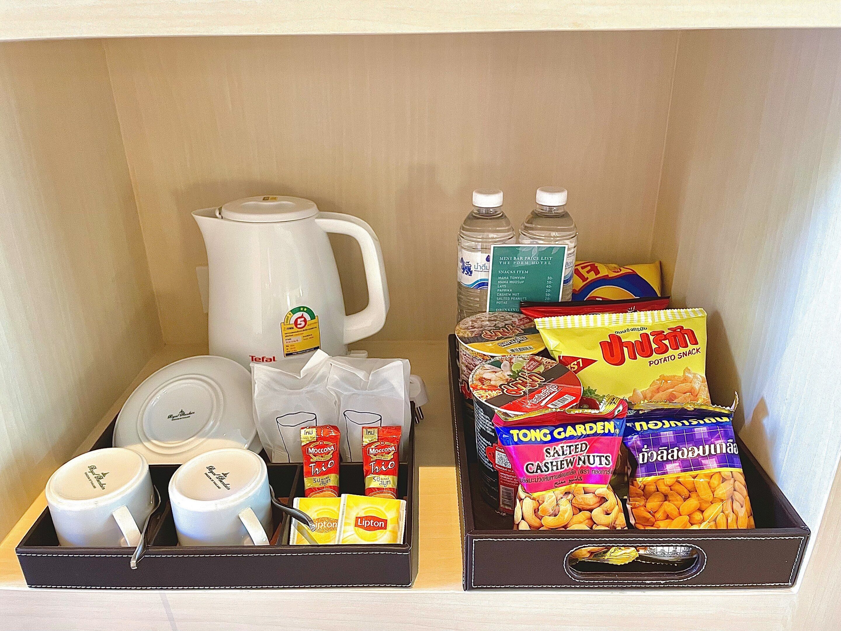A minibar with a coffee maker, bottled water, snacks, and condiments.