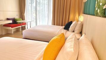 Una camera d'albergo con due letti, una scrivania e una finestra con tende.