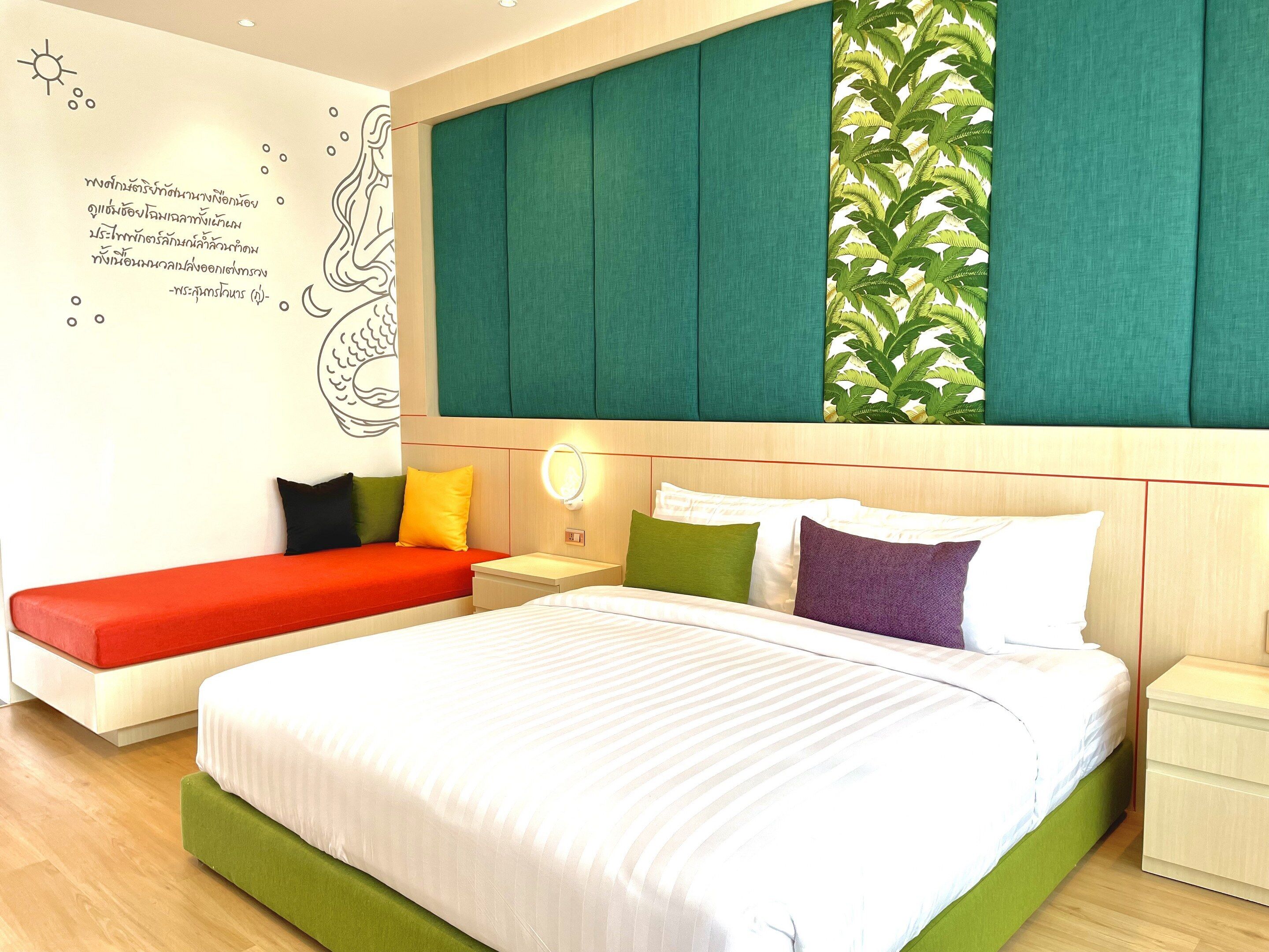 Una habitación de hotel moderna con una cama grande, un banco y una mesita de noche.