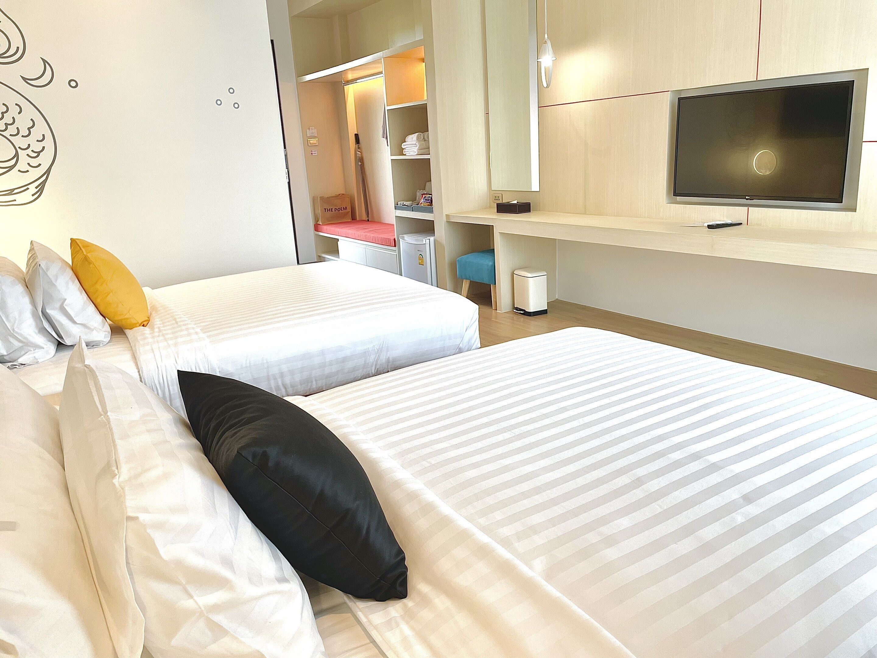A hotel room with two beds, a TV, a wardrobe, and a desk.