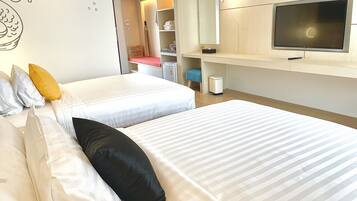 Habitación de hotel con dos camas, televisión, armario y escritorio.