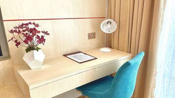 A modern desk with a white vase of flowers, a desk lamp, and a clipboard.