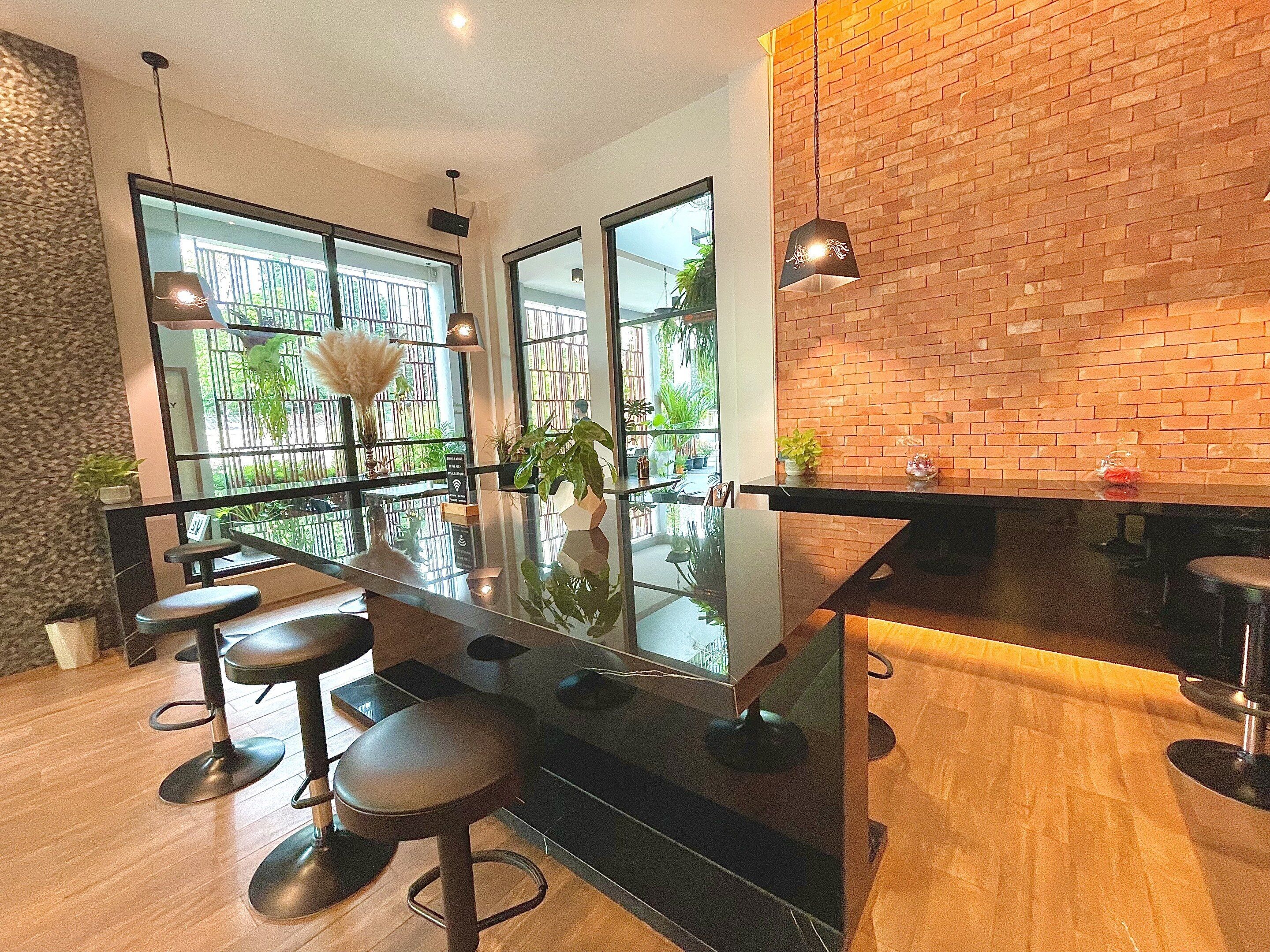 A modern kitchen with a black countertop, bar stools, and a brick wall.